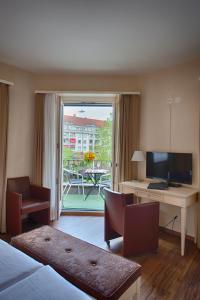 Habitación de hotel con cama, escritorio y TV. en Hotel Neufeld en Zúrich
