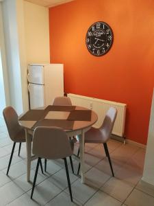 a dining room table with chairs and a clock on the wall at La clé des vacances in Stavelot
