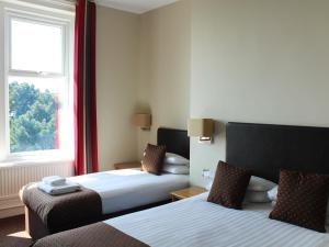 a hotel room with two beds and a television at Chine Hotel in Bournemouth