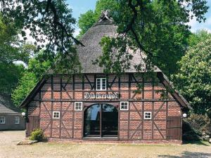 un edificio con tetto di paglia con garage di Glockenhof Studtmann ad Amelinghausen