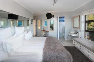 a bedroom with a large white bed and a bathroom at The Nantucket in Hermanus