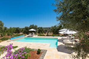 basen z parasolami i fioletowymi kwiatami w obiekcie Villa Sogno Bianco by BarbarHouse w mieście Ostuni