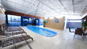a large swimming pool in a large room with chairs at SKY VILLE HOTEL GRAMADO - Localização privilegiada entre Gramado e Canela in Gramado