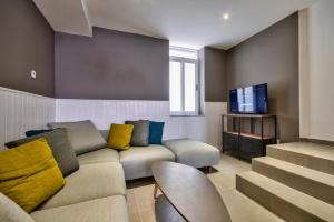 ein Wohnzimmer mit einem Sofa und einem TV in der Unterkunft Amazing 4-bedroom Sliema Town House with Jacuzzi in Sliema