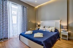 Schlafzimmer mit einem Bett mit blauer Bettwäsche und einem Fenster in der Unterkunft Amazing 4-bedroom Sliema Town House with Jacuzzi in Sliema
