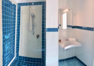 een blauwe betegelde badkamer met een wastafel en een douche bij Klaton Beach Hotel in Formia