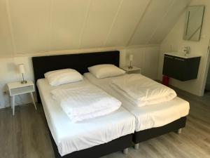 Un dormitorio con dos camas con sábanas y almohadas blancas. en Villa Anna with sauna in Winterswijk, en Winterswijk