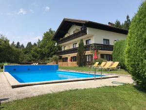a villa with a swimming pool in front of a house at Pension Waldschenke am Wörthersee in Velden am Wörthersee