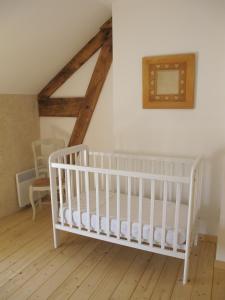 a white crib in a room with wooden floors at Dans l'Air du Temps in Flagey