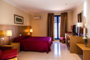 um quarto de hotel com uma cama vermelha e uma televisão em Hostal Casa Manolo em La Senia