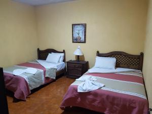 a room with two beds and a table with a lamp at Hotel Nuevo Cupatitzio in Uruapan del Progreso