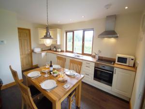a kitchen with a wooden table with chairs and a microwave at LLanddewi Retreat in Llanddewi Ystradenny