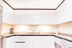 a white kitchen with white cabinets and a sink at Alcam El Coll in Barcelona
