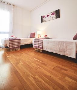 two beds in a room with a wooden floor at Alcam El Coll in Barcelona