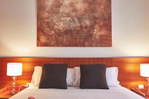 a bed with two pillows and a painting above it at Alcam El Coll in Barcelona