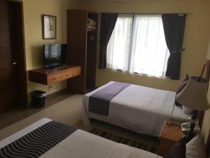 a bedroom with two beds and a television and a window at Hotel Regalo del Alma in Tequisquiapan