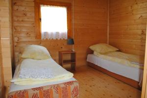a bedroom with two beds in a wooden cabin at Jaskolcze Gniazdo in Dziwnówek