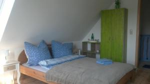 een slaapkamer met een bed met blauwe kussens en een groene kast bij Zum Storchennest in Kemnitz