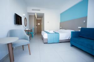 um quarto de hotel com uma cama e um sofá azul em Mandali Hotel em Protaras