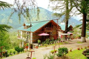 a wooden house with a green roof and some trees at Amara Resorts Manali in Manāli