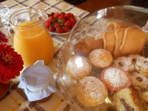 uma mesa com um prato de donuts e um jarro de sumo de laranja em La Tavernetta em Masainas