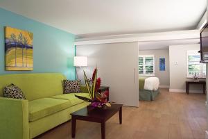 a living room with a green couch and a bedroom at Silver Palms Inn in Key West