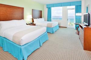 ペンサコーラ・ビーチにあるHoliday Inn Resort Pensacola Beach, an IHG Hotelのベッド2台とテレビが備わるホテルルームです。