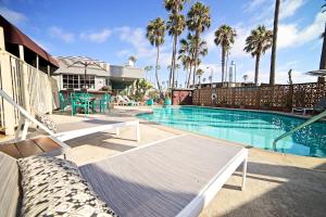 a swimming pool with benches and palm trees at Ocean Villa Inn in San Diego