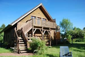 a large wooden cabin with a deck and a chair at FeWo Fleckeby an der Schlei in Fleckeby