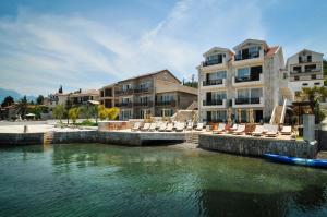 a pool of water with chairs and a building at Apartments Zukovac in Tivat