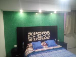 a bedroom with a green wall and a bed with blue pillows at Habitación Puebla Purpura in Puebla