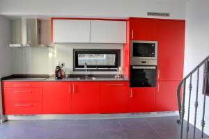 uma cozinha vermelha com um lavatório e um micro-ondas em Casa das Andorinhas em Estreito da Calheta