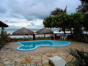 a swimming pool with chairs and umbrellas next to the ocean at Pousada Vira Sol in Trairi