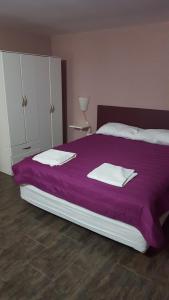 um quarto com uma cama roxa com toalhas em La Pausa em Villa La Angostura