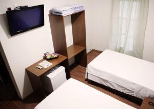 a hotel room with two beds and a tv at Hotel Galeria in Jales