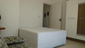 a bedroom with a white bed and a chair at Solar Bella Torres in Passo de Torres