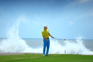 um homem a jogar golfe em frente a uma onda em Las Villas Hotel & Golf By Estrella del Mar em Mazatlán