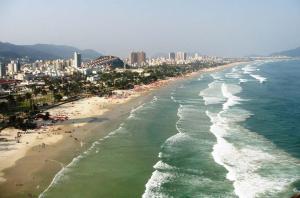 - une vue aérienne sur une plage avec des personnes et des bâtiments dans l'établissement COMFORT GUARUJÁ ENSEADA APARTMENT 26 WIFI, GARAGEM e AR CONDICIONADO, à Guarujá