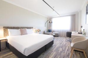 a hotel room with a large bed and a desk at Mermaid Waters Hotel by Nightcap Plus in Gold Coast
