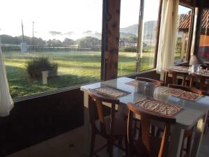 a room with a table with chairs and a large window at Pousada Pica Pau in Urubici