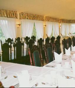 a dining room with a table and chairs and white curtains at Zajazd Kosynier in Węgrzce