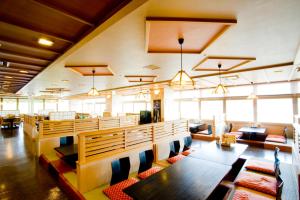 uma sala de jantar com mesas, cadeiras e janelas em Oehonke em Kitami