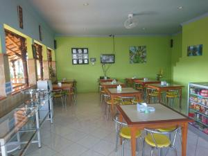 un restaurante con mesas, sillas y paredes verdes en Cerah Hotel, en Paiton