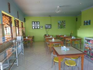 a restaurant with tables and chairs and green walls at Cerah Hotel in Paiton