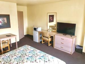 Habitación de hotel con cama, escritorio y TV. en Travelers Inn Motel, en Salem