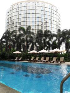 a swimming pool with chairs and a large building at Bluesky Serviced Apartment Airport Plaza in Ho Chi Minh City