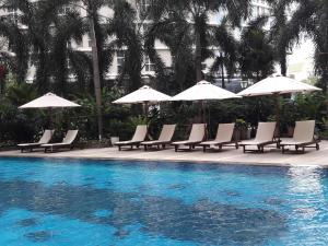 a group of chairs and umbrellas next to a swimming pool at Bluesky Serviced Apartment Airport Plaza in Ho Chi Minh City