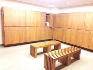 a locker room with two benches and wooden lockers at Bluesky Serviced Apartment Airport Plaza in Ho Chi Minh City