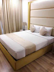 Bluesky Serviced Apartment Airport Plaza في مدينة هوشي منه: غرفة نوم بسرير كبير عليها شراشف ووسائد بيضاء