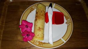 a plate with a piece of food and flowers on it at Herry Homestay Kuta Lombok in Kuta Lombok
